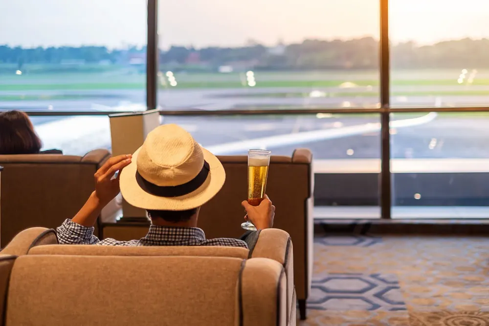 Man holding a full glass of beer in an airport terminal